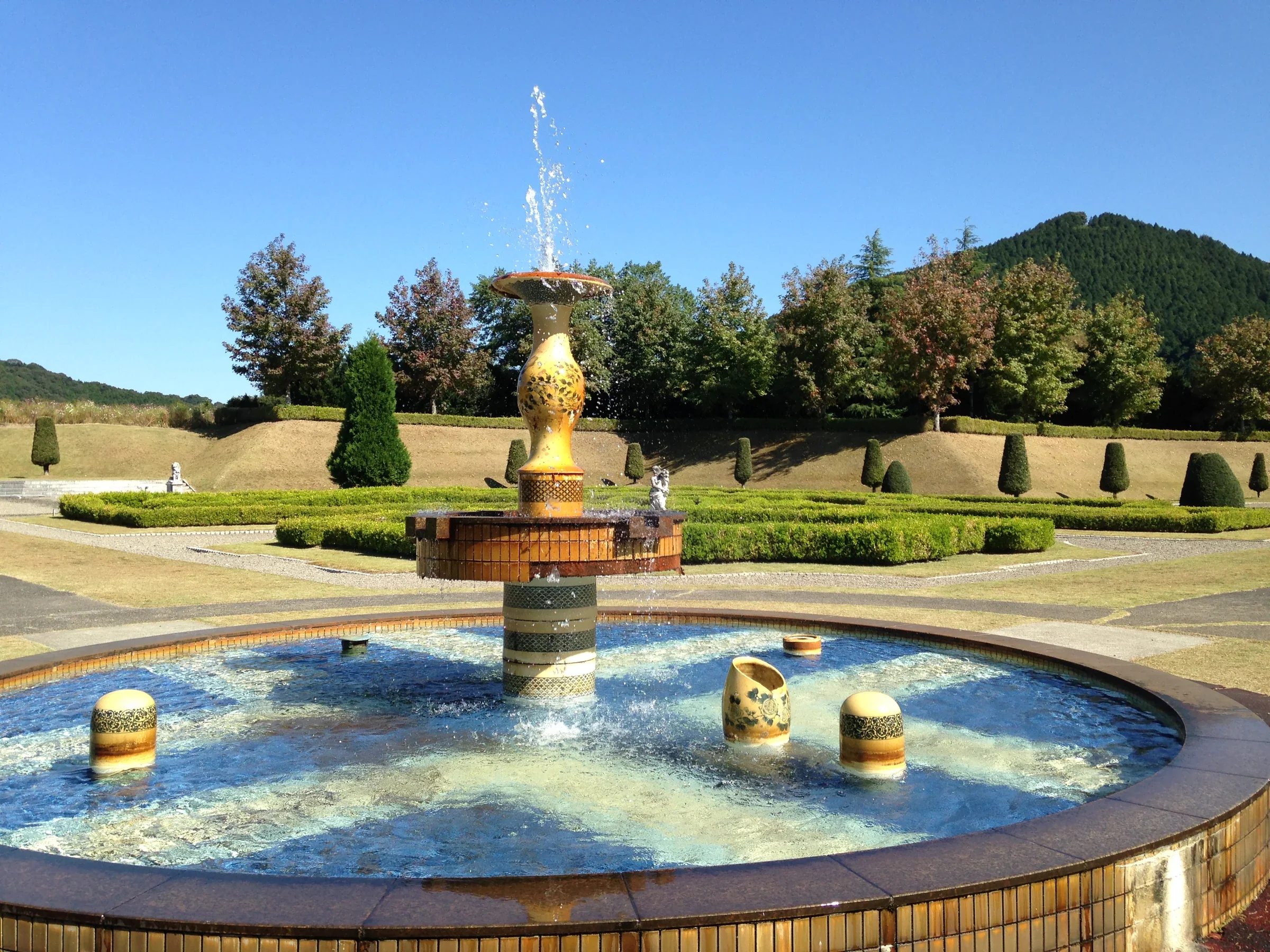有田陶瓷公園庭園的有田燒瓷器噴泉，周圍是修剪整齊的草地與山景