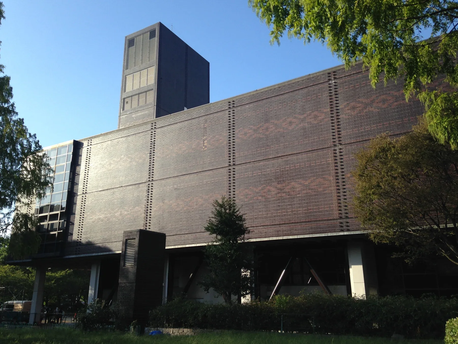 福岡縣立美術館深色磚牆外觀，樹影落在建築前方
