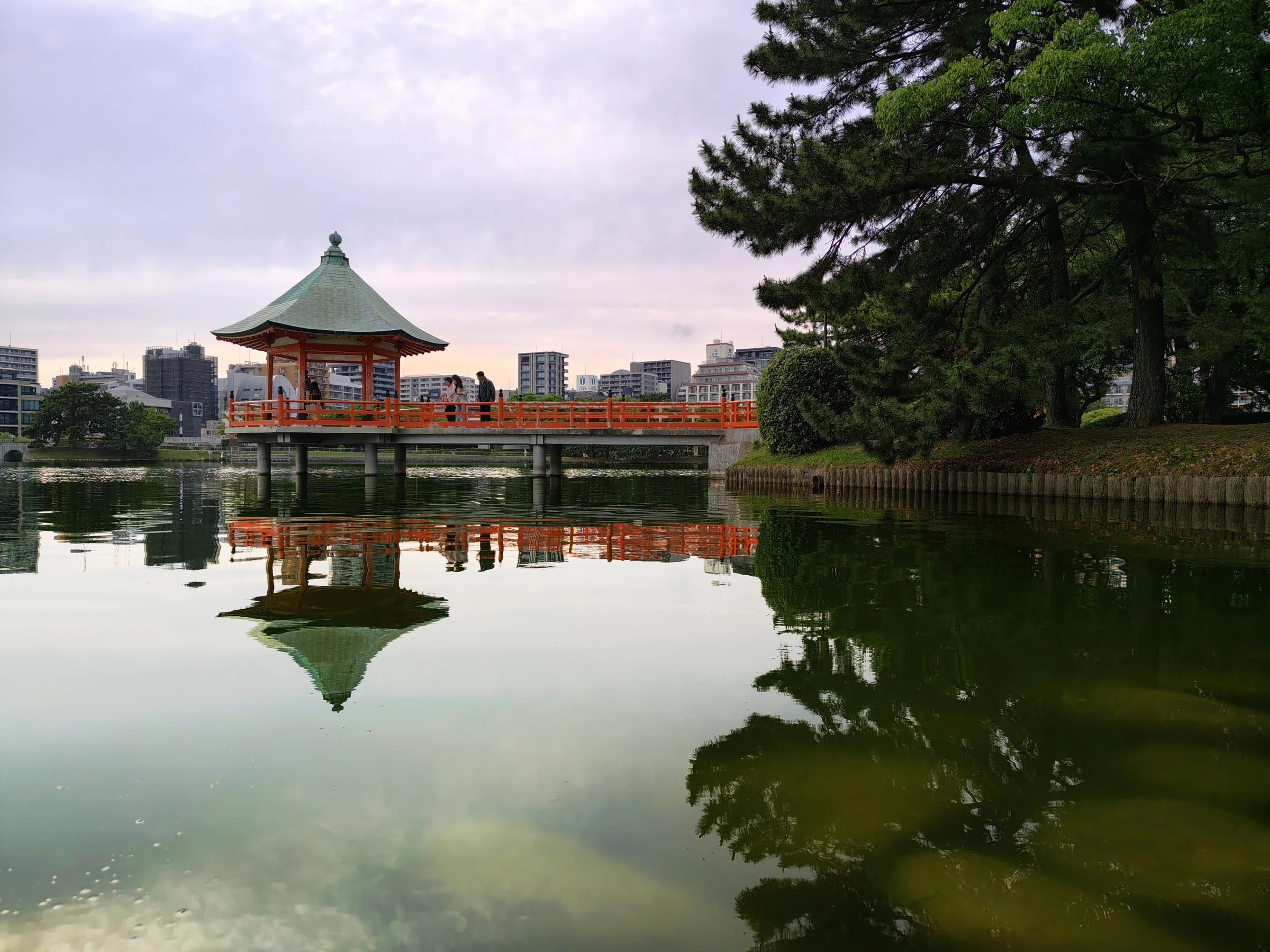 大濠公園浮見堂南側向外伸出湖面，水面映出橋身與松樹