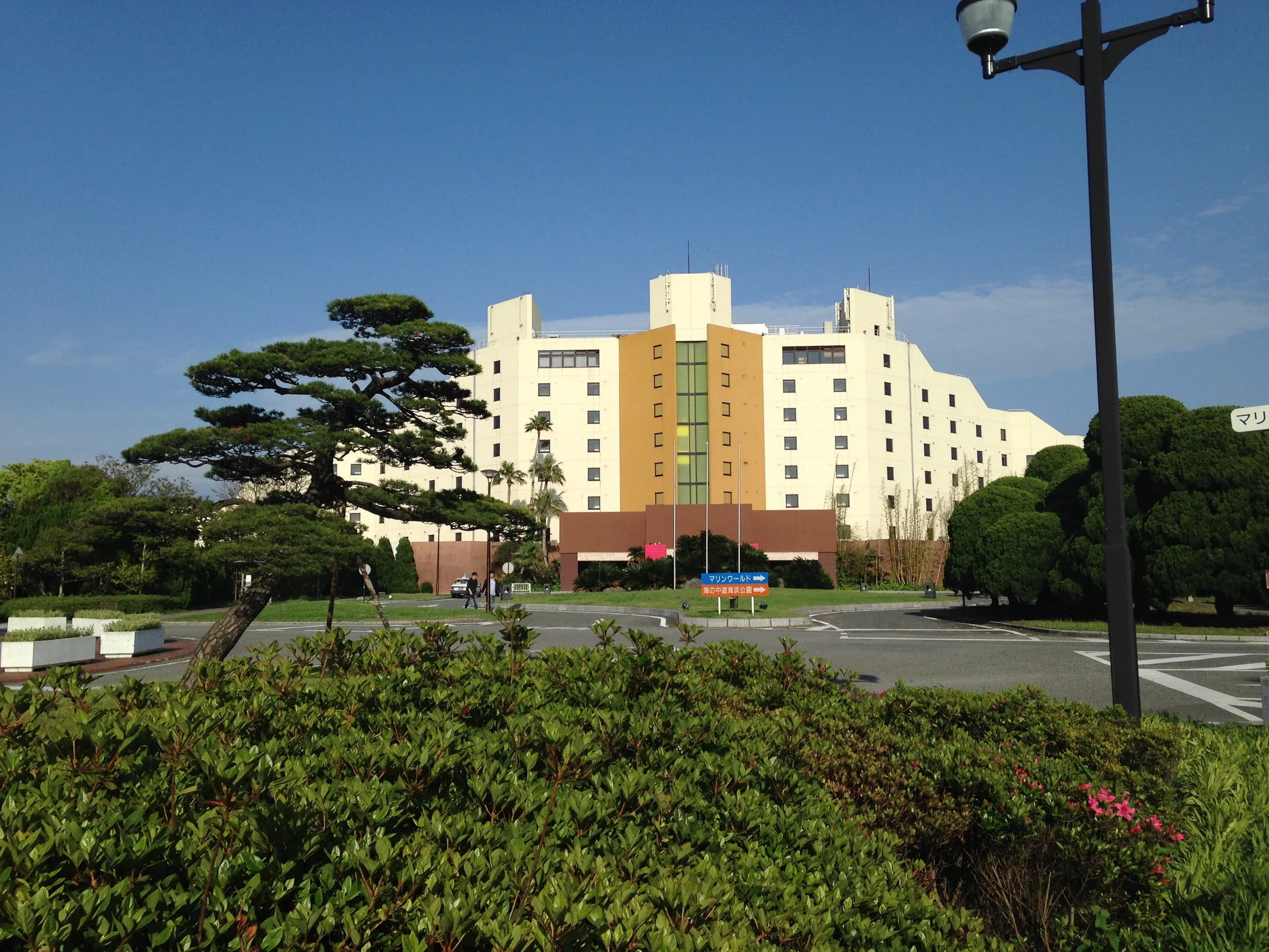 從海之中道站附近道路望向 THE LUIGANS 飯店，前景是綠植與道路