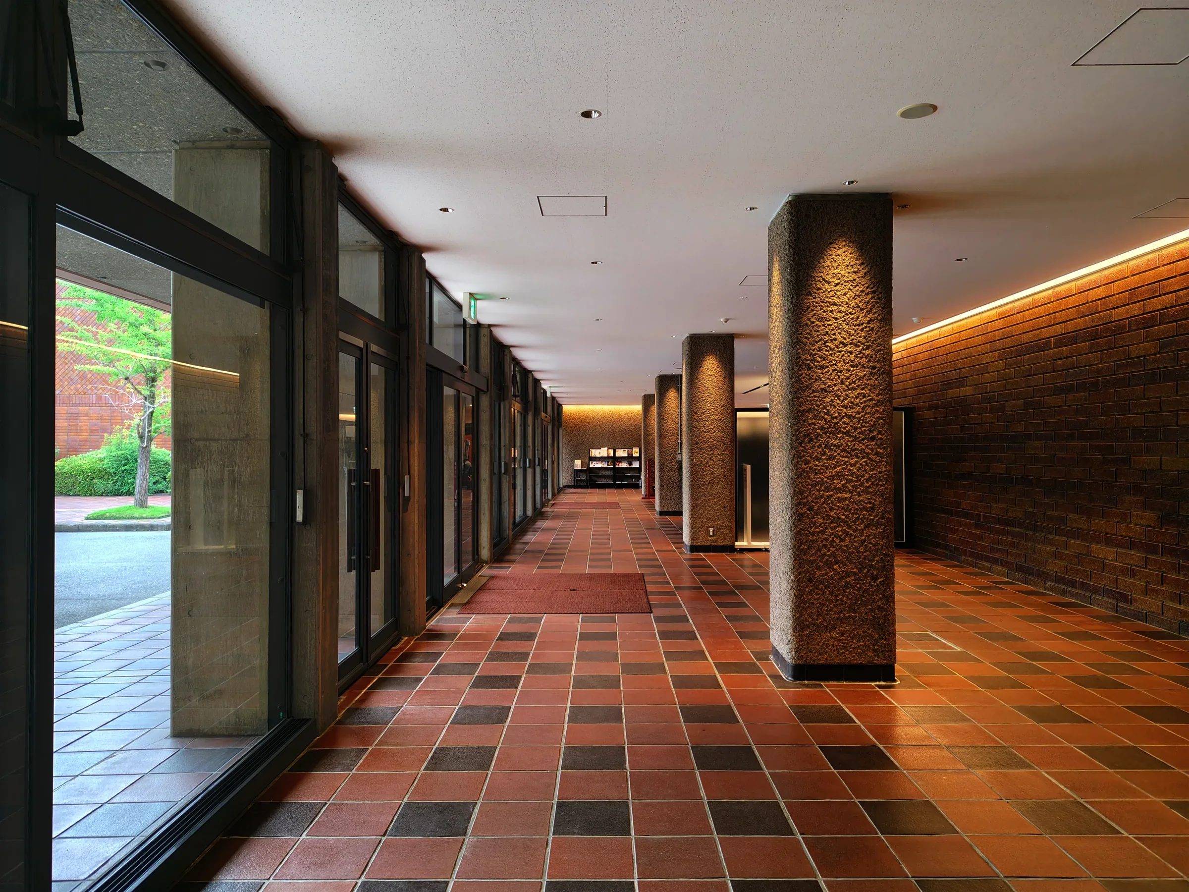 福岡市美術館一樓大廳的玻璃窗、柱列與紅棕色地磚