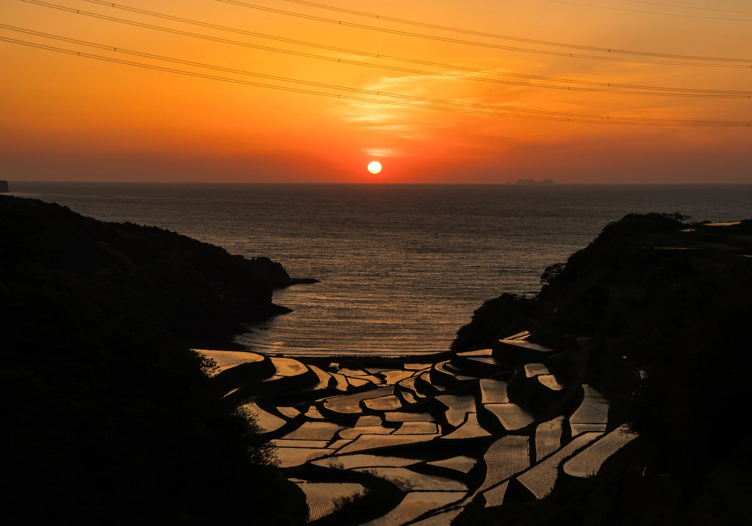 佐賀縣玄海町浜野浦梯田沿海層層延伸，遠方海灣映著晚霞