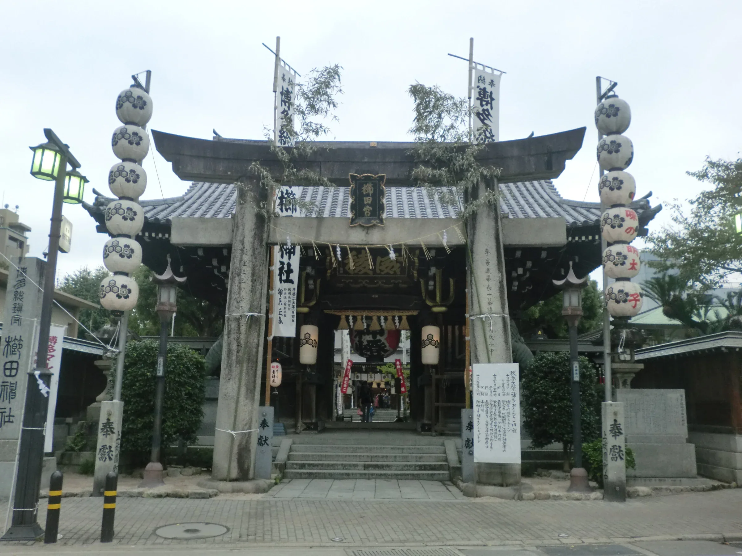 博多おくんち當日的櫛田神社，鳥居前掛有燈籠與祭典告示