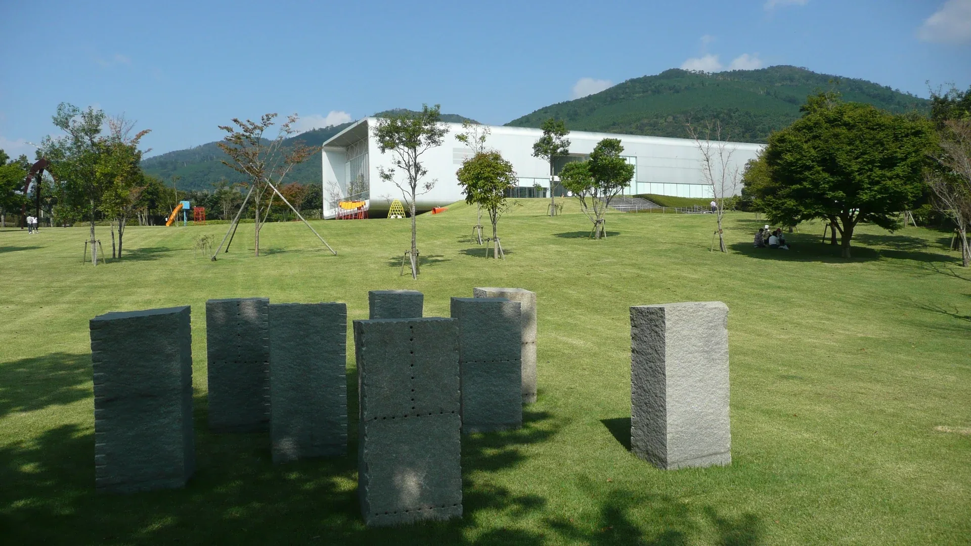霧島藝術之森戶外草地、作品與白色展館，背景是栗野岳山林
