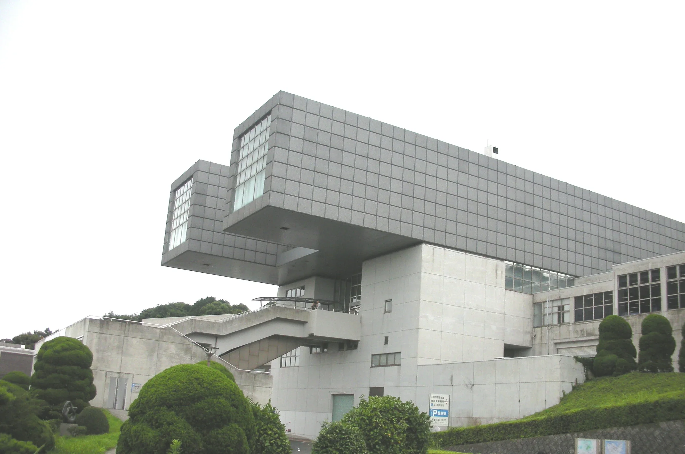 北九州市立美術館本館外觀，上層方形量體延伸到坡地庭園上方