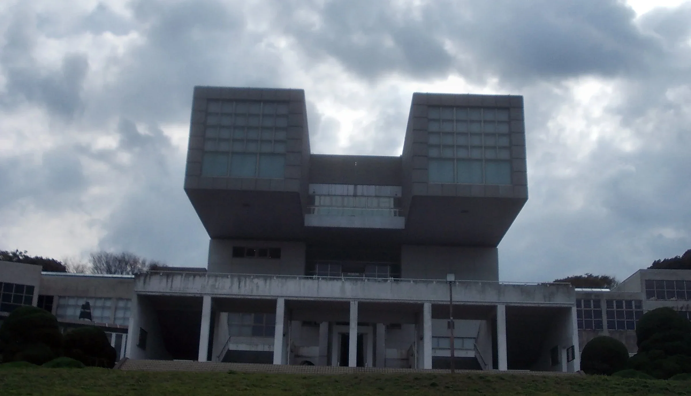 北九州市立美術館本館外觀，兩座方形量體從草坡上方伸出