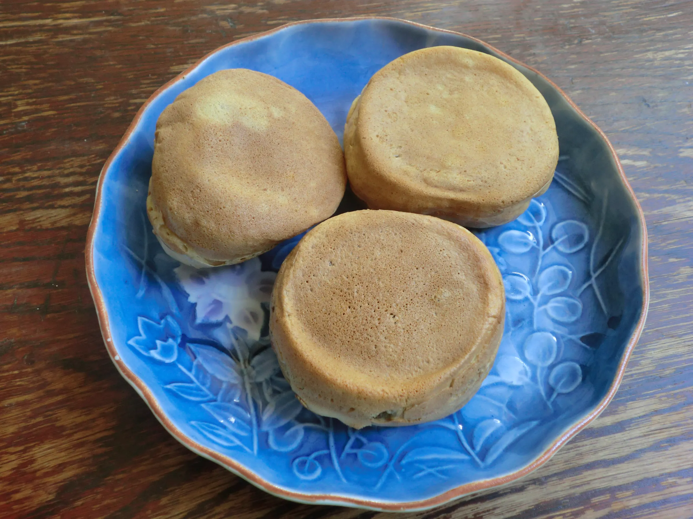 藍色盤子裏的三個蜂樂饅頭，表面烤成淺金黃色