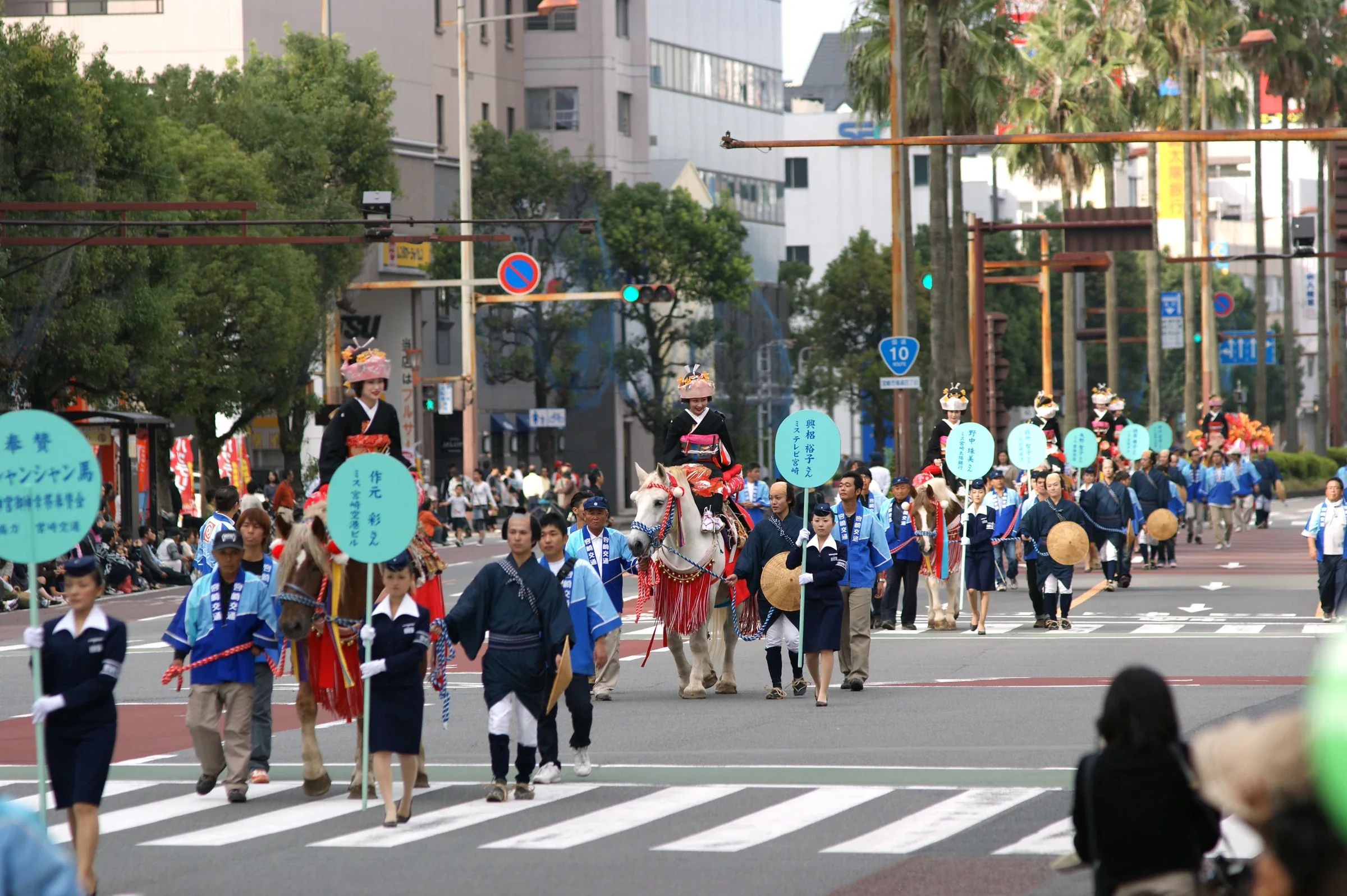 宮崎神宮大祭御神幸行列沿市中心道路前進，隊伍中有騎馬隊列與穿傳統服飾的參加者