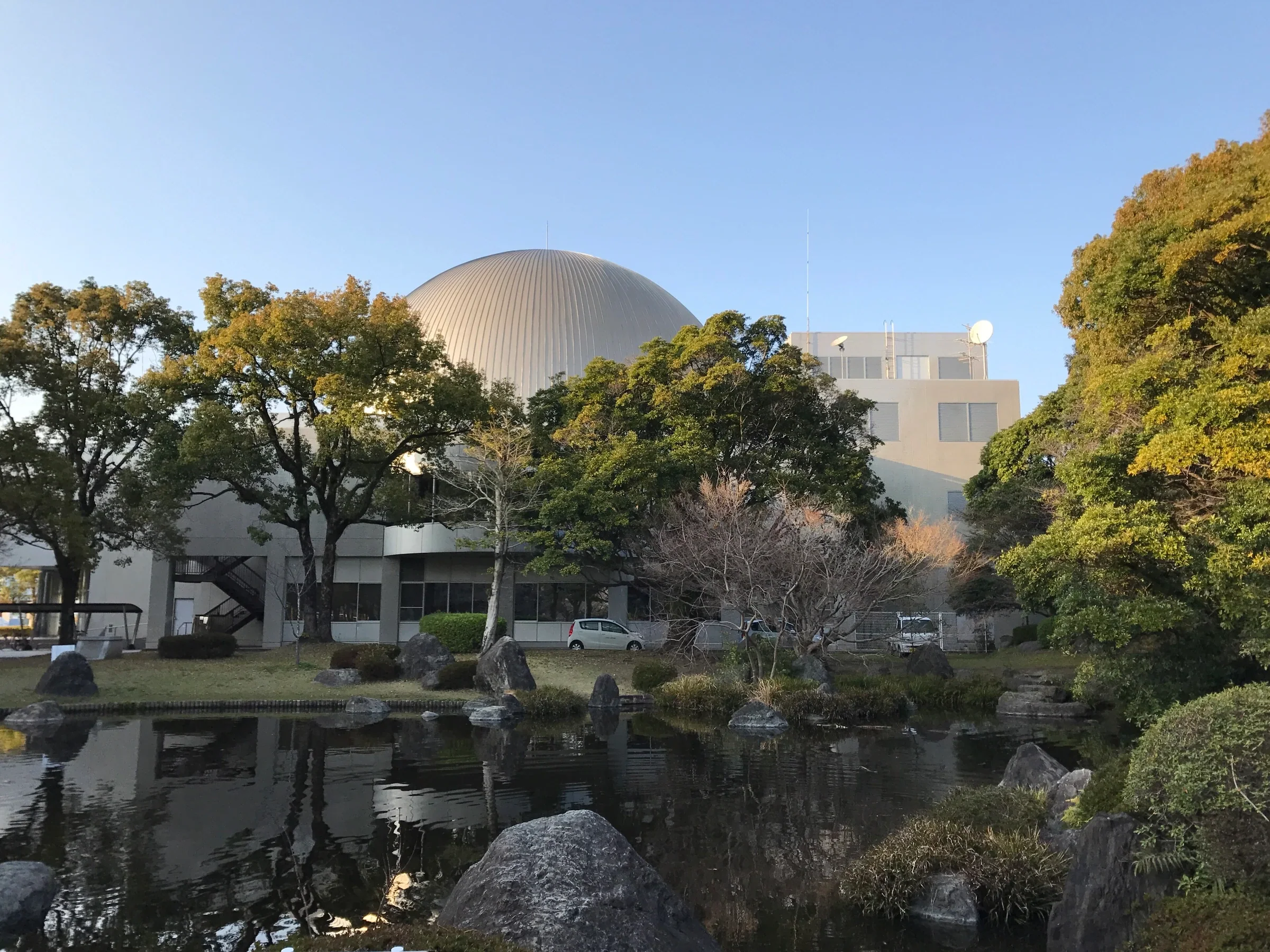 宮崎科學技術館圓頂與宮崎中央公園水池相映，園舍鄰接公園步道