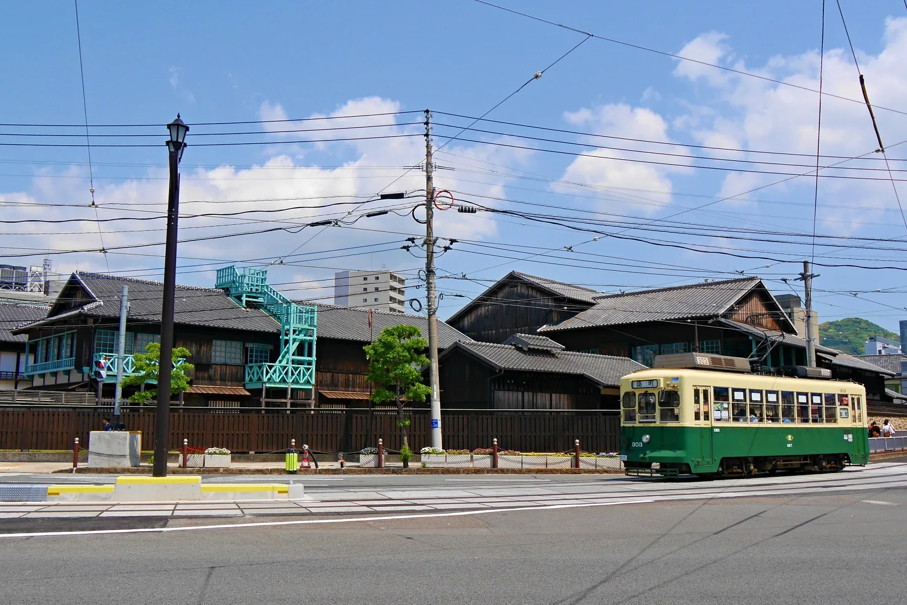 出島復原建築旁有一輛行經長崎市區的綠色路面電車