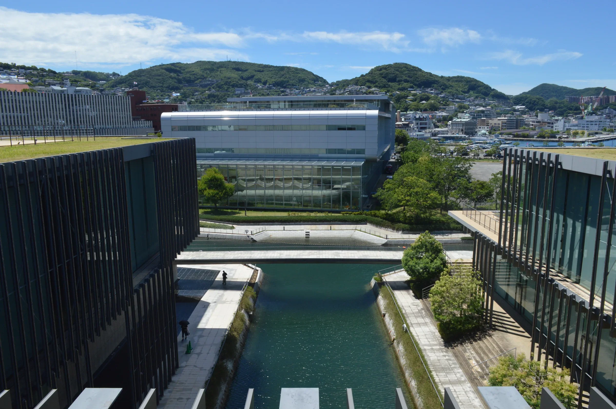 從長崎縣美術館空中回廊望向另一棟館舍、運河與遠處的長崎山坡住宅