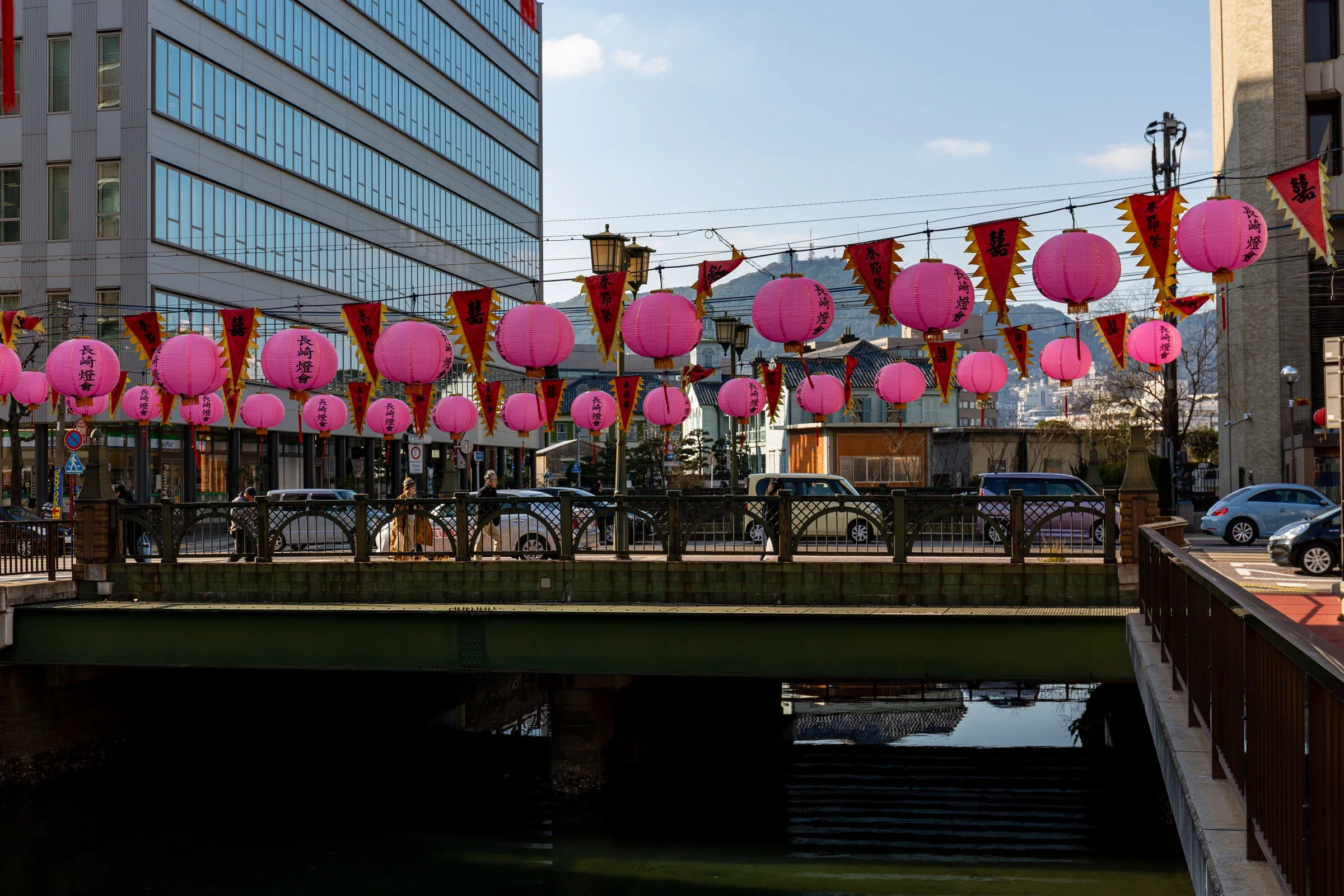 2019 年銅座川橋上懸掛粉紅色長崎燈籠，河道與市區建築在日光下可見