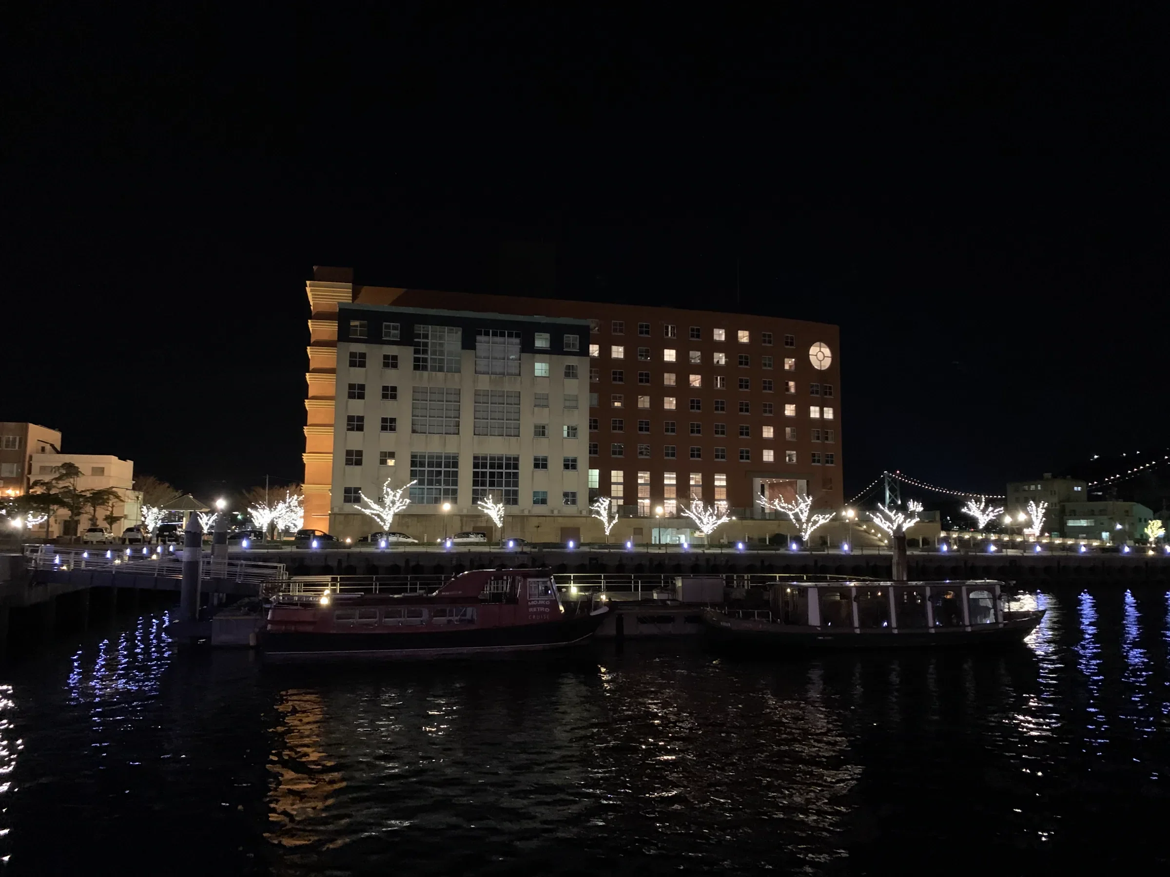 夜晚從門司港水邊望向普樂美雅酒店亮燈的客房與關門橋