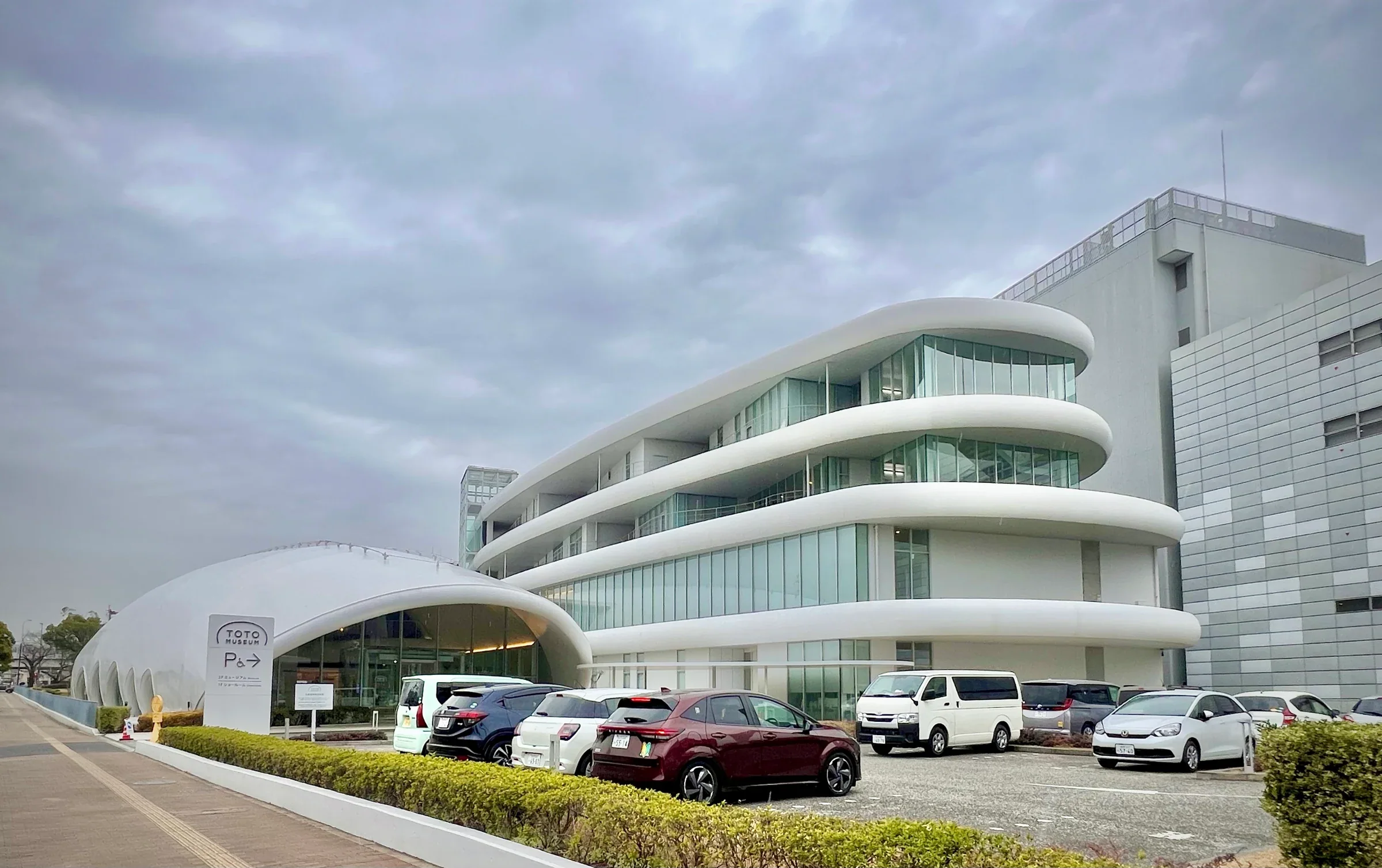 2026年2月TOTO Museum白色曲線館舍與前方停車區，非特展展場