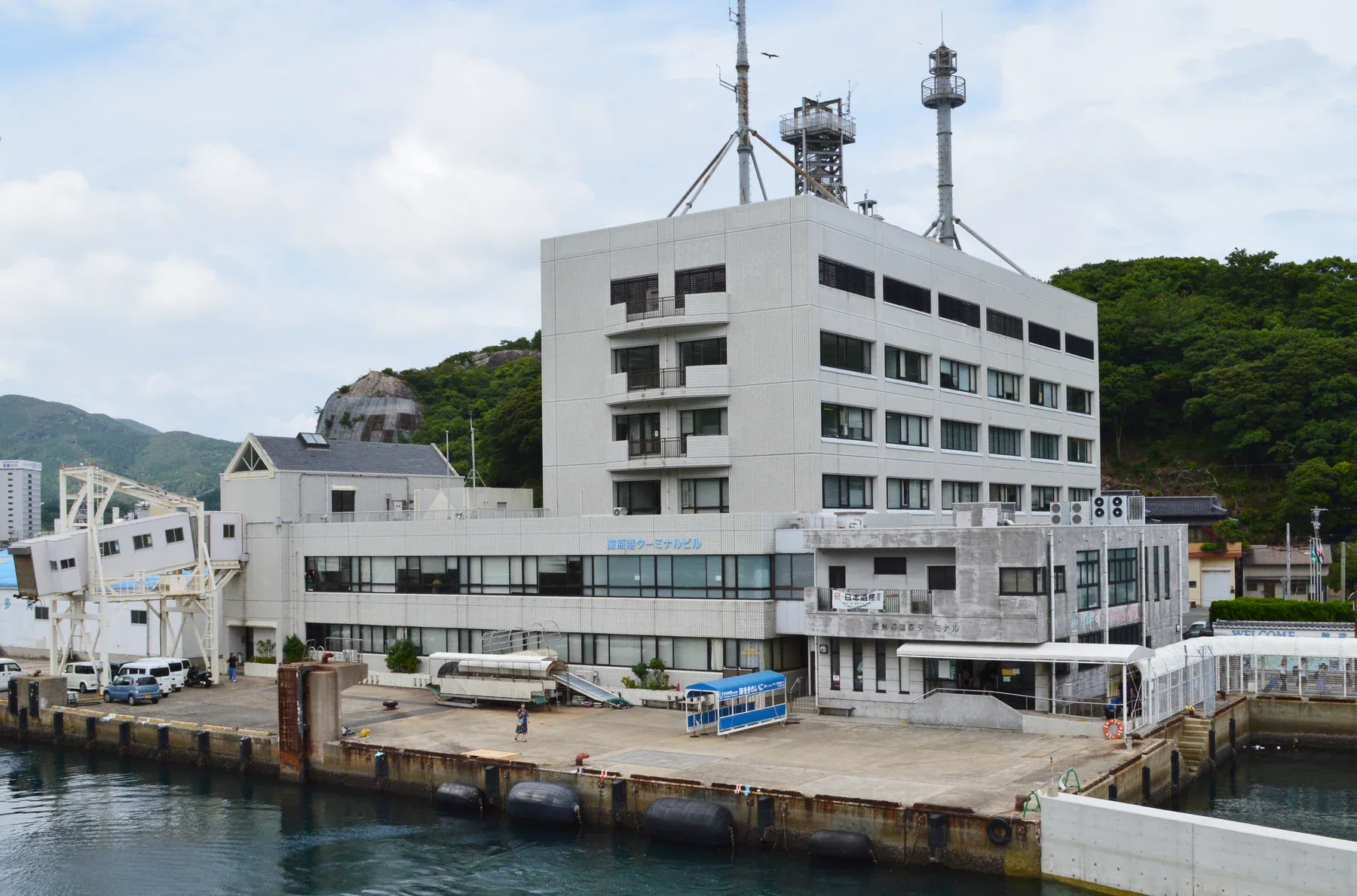 從海面望向對馬嚴原港，渡輪碼頭與港邊街區沿岸展開
