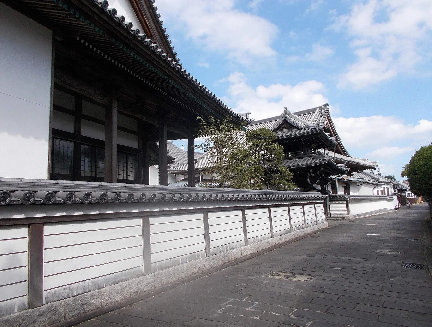 臼杵二王座歷史之道白天街景，白壁和寺院屋瓦沿石板路延伸